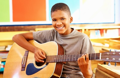 child with a smile holding a 
guitar